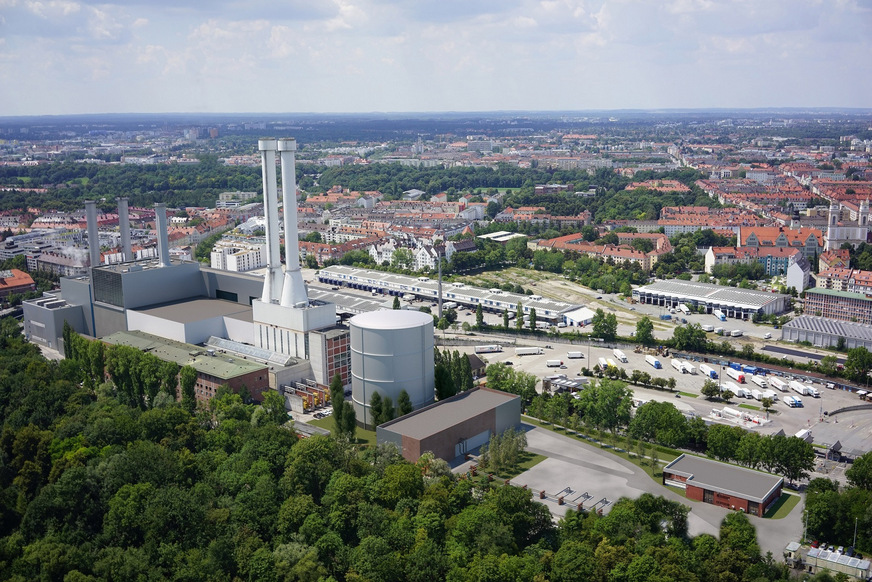 Die Visualierung zeigt den künftigen Energiestandort Süd aus der Vogelsperspektive. Neben dem HKW Süd (links) steht der Wärmespeicher, rechts daneben das Technikgebäude mit der Wärmeeinbindung und daneben die Bohrungen der Geothemieanlage.