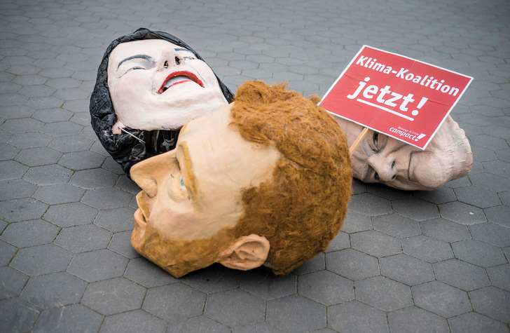 Masken der führenden Köpfe der künftigen Ampel-Koalition von einer Demo ermahnen die Verhandlungsführer des Ampelbündnisses, eine Klimakoalition zu werden.
