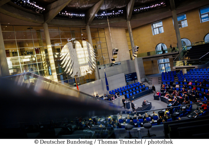 Die tief stehende Sonne beleuchtet den Plenarsaal: Blick auf den Bundestagsadler und ins Plenum.