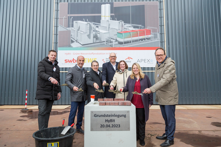 Legen den symbolischen Grundstein für das Wasserstoff-Projekt "HyBit" in Bremen: v.l.n.r.: Peter Rößner (CEO Apex), Stefan Dohler (EWE-Vorstandsvorsitzender), Karsten Schneiker (SWB-Vorstand), Andreas Bovenschulte (Bürgermeister), Kristina Vogt (Wirtschaftssenatorin), Maike Schaefer (Senatorin für Klimaschutz und Stadtentwicklung), Rainer Blaschek (Vorsitzender der Geschäftsführung von Arcelor-Mittal).