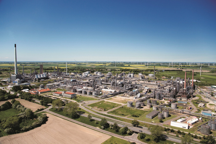 Die Raffinerie Heide in Hemmingstedt, Produktionsanlagen mit Windkraftanlagen im Hintergrund.