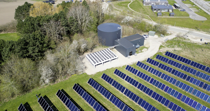 Die Großwärmepumpe von Solrød (Mitte) steht zwischen der Solarthermieanlage (darunter) und dem Wärmespeicher (darüber) in einigem Abstand zur Wohnbebauung. - © Foto: Aalborg CSP
