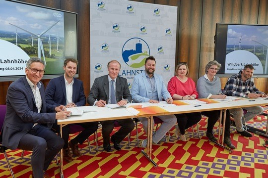 Die Vertragsunterzeichnung in der Lahnsteiner Stadthalle: am Tisch (von links) Dr. Steffen Weil und Christoph Hesse (beide evm), Privateigentümer Sebastian Graf von Kanitz, Oberbürgermeister Lennart Siefert (Lahnstein), die Ortsbürgermeisterinnen Michaele Lehmler (Becheln) und Sonja Puggé (Schweighausen) sowie Ortsbürgermeister Andreas Schilbach (Frücht). - © Matthias Brand / evm
