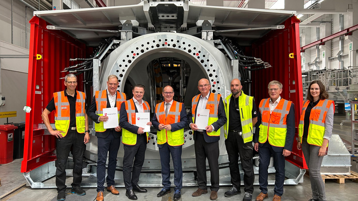 Bildunterschrift: (v.l.n.r.) Volker Trebesch (Enercon Betriebsrat), Wiard Siebels (MdL Niedersachsen), Udo Bauer (Enercon CEO), Grant Hendrik Tonne (Wirtschaftsminister Niedersachsen), Michael Jaxy (Enercon CFO), Kevin Kebel (Enercon Konzernbetriebsrat, Horst Feddermann (Bürgermeister Stadt Aurich), Lena Trebesch (Sales & After Sales Managerin für Norddeutschland) bei der Förderbescheidübergabe vor einer E-Gondel im Enercon Kompetenzzentrum Mechatronic in Aurich.