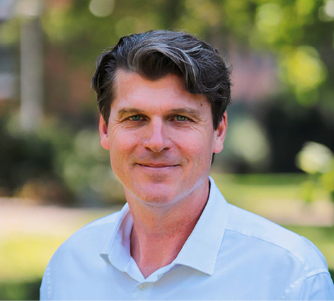 Mann mit kurzen braunen Haaren im weißen Hemd lächelt im Freien mit Grünzeug im Hintergrund. - © Foto: Mingyang Smart Energy