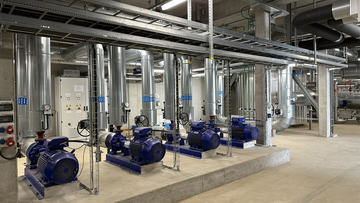 Vier blaue Industriepumpen mit Leitungen und Messgeräten in einem sauberen, modernen Maschinenraum mit Betonboden. - © ABB