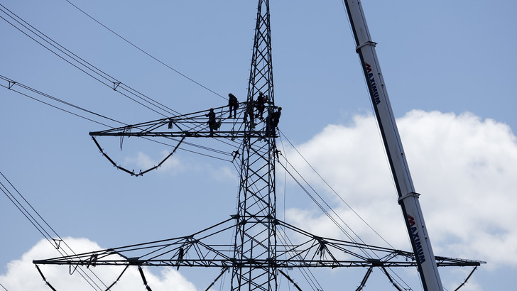 Freileitungsmonteure beim Aufbau eines neuen Strommastes.
