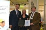 Qualitätszertifikat BayWa Eicke Weber Beate Mand, Matthias Taft | Beate Mand vom VDE (Mitte) und Eicke Weber vom Fraunhofer ISE (rechts) haben Matthias Taft von BayWa (links) das Zertifikat auf dem Stand des Unternehmens auf der Intersolar 2016 übergeben.