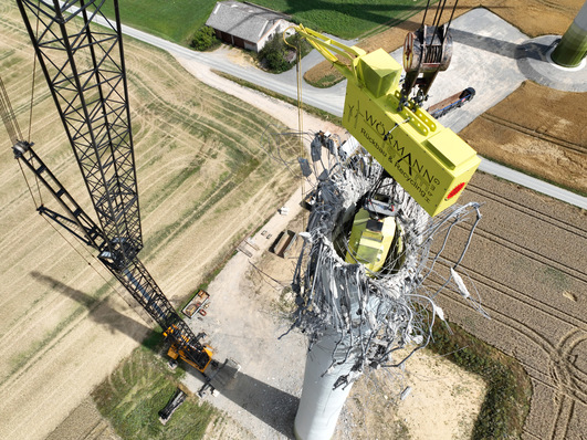 Rückbau eines Betonturms mit einer Traverse. Diese Technik von Wörmann-Team vermeidet, dass der Turm gefällt werden muss.