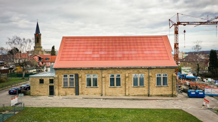 Bei Bestandsgebäuden glit die Regel: Je unsichtbarer die Solaranlage ist, desto höher ist die Akzeptanz. Wie so etwas geht, zeigt dieses Projekt der denkmalgeschützten Turnhalle in der Stadt Eppingen, die mit ziegelrot gefärbten Morpho-Color-Modulen eingedeckt ist.