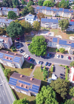 Luftaufnahme eines Vorortviertels mit Solarmodulen auf den Dächern, umgeben von Bäumen und Straßen. - © Foto: Mainova AG