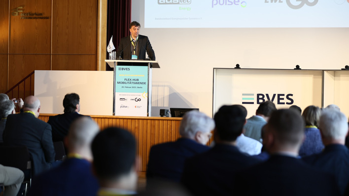 Mann spricht während einer Konferenz an einem Podium in einem großen Raum mit sitzendem Publikum. - © William Veder - BVES