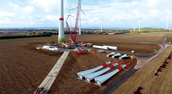 Eine im Bau befindliche Windkraftanlage auf einem Feld, mit Turbinenblättern und Ausrüstung, die auf dem Boden ausgebreitet sind. - © GAIA mbH, Lambsheim
