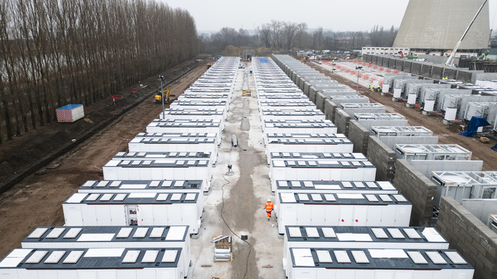 Reihen weißer provisorischer Wohneinheiten säumen eine Baustelle mit Arbeitern und Bäumen im Hintergrund. - © engie