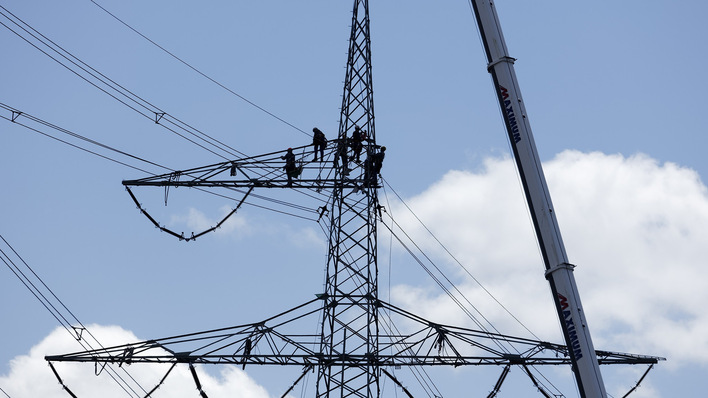 Freileitungsmonteure beim Aufbau eines neuen Strommastes.